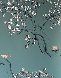 two monkeys are sitting on the branches of a tree with white flowers in front of a blue background