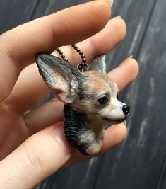 a hand holding a small dog necklace on it's finger