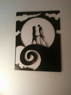 the silhouettes of two people are shown in this paper cut art piece, which is hanging on the wall