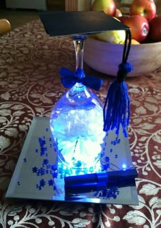 a glass bottle with blue lights on it sitting on top of a table next to apples