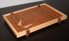 a wooden tray sitting on top of a black table with an arrow drawn on it