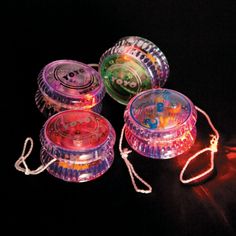 three round plastic containers with string attached to them on a black surface, in the dark