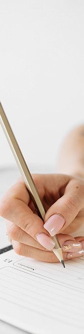 a woman's hand holding a pen and writing on a paper