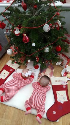 a christmas tree is decorated with red and white stocking, baby's feet in the stockings