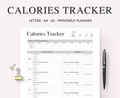 the calories tracker is on top of a piece of paper next to a pen