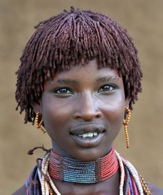 a woman with dreadlocks on her head and wearing necklaces around her neck