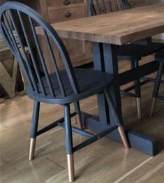 a wooden table with two blue chairs next to it on a hard wood floor in a kitchen