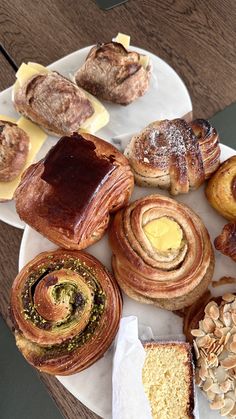 an assortment of pastries on a plate with buttered breads and other baked goods