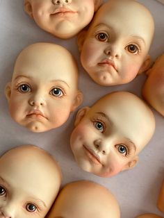 six baby dolls with different facial expressions on their faces, all facing the same direction