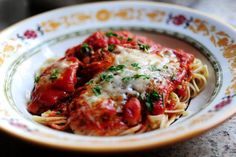 two meatballs covered in marinara sauce and parmesan cheese on a plate