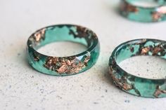 Looking for an unconventional alternative ring? The faceted jade green band will help you stand out in a crowd. Being so lightweight, you can wear only one or you can stack two or three on a finger. The resin ring contains rose gold leaf suspended in hand pigmented resin. Height: 5.5 mm Width: 2.4 mm We suggest that you order half a size up from your usual ring size when purchasing a wide band. Wide bands do not leave the tell-tale 'ring mark' on your finger when you take it off, thanks to their greater width. Handmade by me from scratch, each one of my pieces is hand pigmented, and poured into a silicone mold. After I remove it from the mold I hand sand it for you to have a smooth and comfortable piece to wear. Please take into consideration that on some computer monitors the picture and Alternative Ring, Verde Jade, Ring Resin, Rose Gold Leaf, Traditional Engagement Rings, Faceted Ring, Resin Ring, Gold Flakes, Matching Bracelets