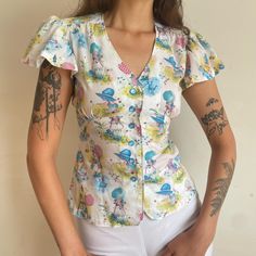 "This is an adorable Holly Hobbie printed blouse from the 1960s. It features flutter sleeves, buttons down the front, and a tie at the back. No label tag Fits Small-Medium Bust 36-38\" Waist 28\" Sleeve 6\" Length 22\" Cotton Great condition" Vintage Printed V-neck Top, Retro Fitted Short Sleeve Blouse, Vintage Printed V-neck Blouse, Cottagecore Spring Top With Buttons, Retro Summer Button-up Blouse, Retro Button-up Summer Blouse, Vintage Fitted Printed Tops, Retro Printed Spring Blouse, Fitted Short Sleeve Tops In 1950s Style