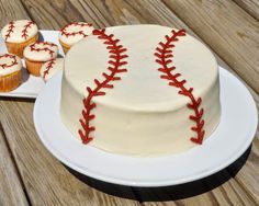 a baseball themed cake and cupcakes on a wooden table with wood planks