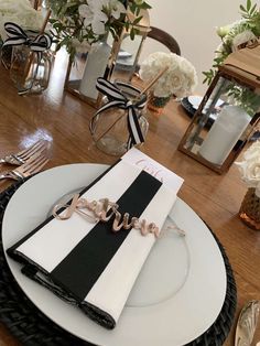 a place setting with black and white napkins, silverware and flowers on the table