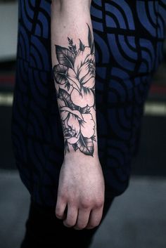 a woman's arm with flowers on it and a ring around the wrist tattoo