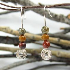 These earrings are handcrafted from one continuous piece of sterling silver wire. The bottoms are coiled into an informal spiral and then topped with multi-colored jasper stones. The stones are earthy colors - mottled green, dark mustard yellow and dark, earthy brick-red. The earthy colors and spiral give them a natura #firmalo Dark Mustard Yellow, Wire Jig, Fine Silver Jewelry, Jasper Earrings, Making Earrings, Wrapped Jewelry, Jasper Stone