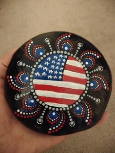 a painted rock with an american flag on it in someone's hand and the colors are red, white, and blue