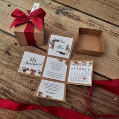 the wedding stationery is laid out on top of the wooden table and tied with a red ribbon