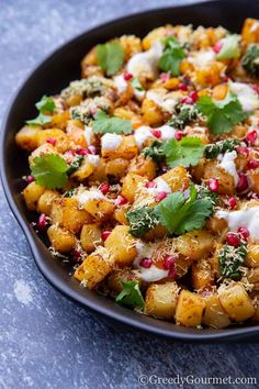 a pan filled with potatoes covered in sour cream and garnished with cilantro