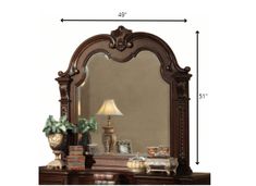 a large mirror sitting on top of a wooden dresser next to a lamp and potted plant