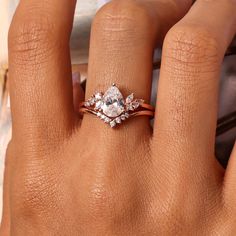 a woman's hand with a diamond ring on her left hand and the other hand holding an engagement ring