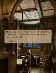 a person sitting at a table in front of a book shelf with a quote on it