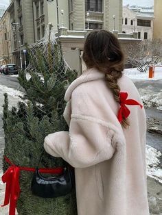 a woman in a fur coat carrying a christmas tree