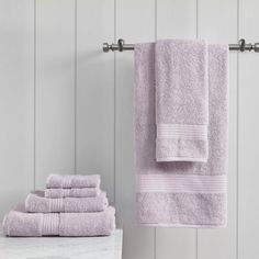 towels are stacked on a towel rack next to a marble countertop and white walls