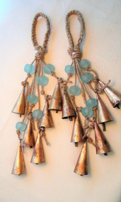 a pair of bells hanging from a rope on top of a white wall with blue glass beads