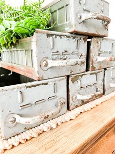 four metal boxes with plants in them are stacked on top of each other near a planter