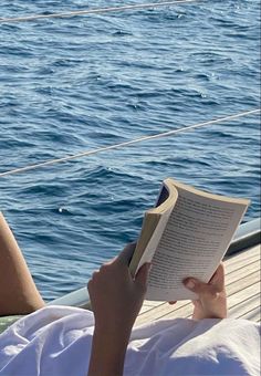 a woman reading a book while sitting on a boat