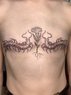 a woman's back with tattoos on her chest and two flowers in the center