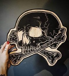 a person is drawing a skull and crossbones on a piece of wood that has been cut out