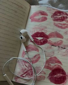 an open notebook with red lipstick drawn on it and headphones attached to the book