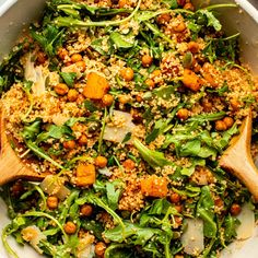 a salad with carrots, spinach and chickpeas in a white bowl