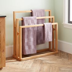 three towels are hanging on a wooden rack