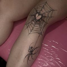 a person with a spider tattoo on their arm and leg sitting on a pink surface