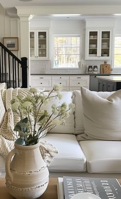 a living room filled with furniture and a white couch next to a table covered in pillows