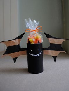 a halloween treat in a black tube with bats on the side and candy inside it