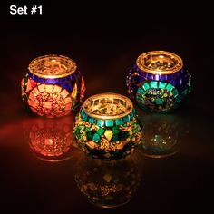 three colorful glass candles are sitting on a table