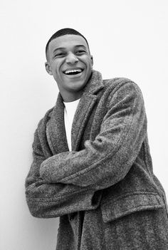 a black and white photo of a smiling man with his arms folded over his chest