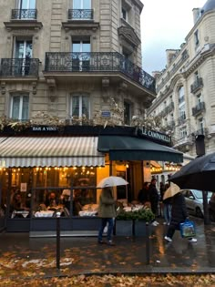 people are walking in the rain with umbrellas near an outdoor cafe on a rainy day