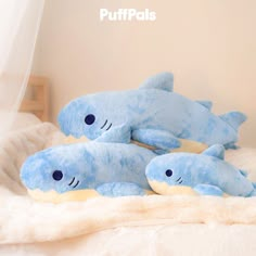 two blue stuffed animals laying on top of a bed