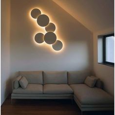 a living room with a couch and round lights on the wall above it's windows