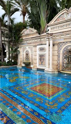 an outdoor swimming pool surrounded by palm trees and tiled flooring with colorful tiles on it