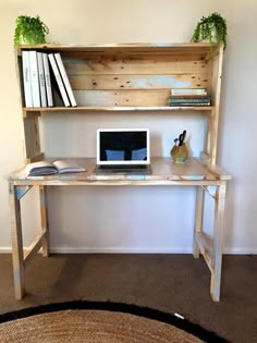 a desk with a computer on top of it and bookshelf above the desk