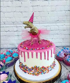 a birthday cake with sprinkles and a dinosaur on top