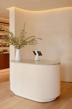 a white reception table with two vases on it and a plant in the center