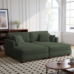 a living room with a large green couch and coffee table in front of a window