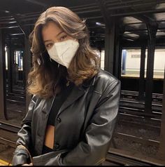 a woman wearing a face mask standing on a train platform